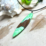 Anhänger aus Nussbaumholz und fluoreszierendem Epoxidharz in Grün-Weiß. Größe ca. 5,8 × 2 cm, Edelstahlöse, Lederkette 45+5 cm. Handgefertigtes Unikat.