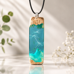 Maserholz Anhänger „Windlicht“ mit echten Pusteblumensamen in türkisfarbenem Epoxidharz an schwarzer Lederkette. Handgefertigter Unikat-Schmuck mit Hochglanz-Finish. Die schwebenden Samen und das leuchtende Türkis erinnern an einen eingefangenen Windhauch und die Schönheit der Natur.