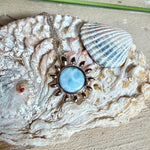 Feine Halskette aus rhodiniertem 925 Silber mit Sonnen-Anhänger und rundem Larimar-Cabochon, 10 mm. Der seltene, hellblaue Stein aus der Dominikanischen Republik erinnert an Meer und Himmel. Gesamtgröße des Anhängers ca. 20 x 19 mm, Ankerkette 45 cm, ca. 1 mm stark. Edler, maritimer Schmuck, geliefert in einer Geschenkbox.