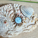 Feine Halskette aus rhodiniertem 925 Silber mit Sonnen-Anhänger und rundem Larimar-Cabochon, 10 mm. Der seltene, hellblaue Stein aus der Dominikanischen Republik erinnert an Meer und Himmel. Gesamtgröße des Anhängers ca. 20 x 19 mm, Ankerkette 45 cm, ca. 1 mm stark. Edler, maritimer Schmuck, geliefert in einer Geschenkbox.