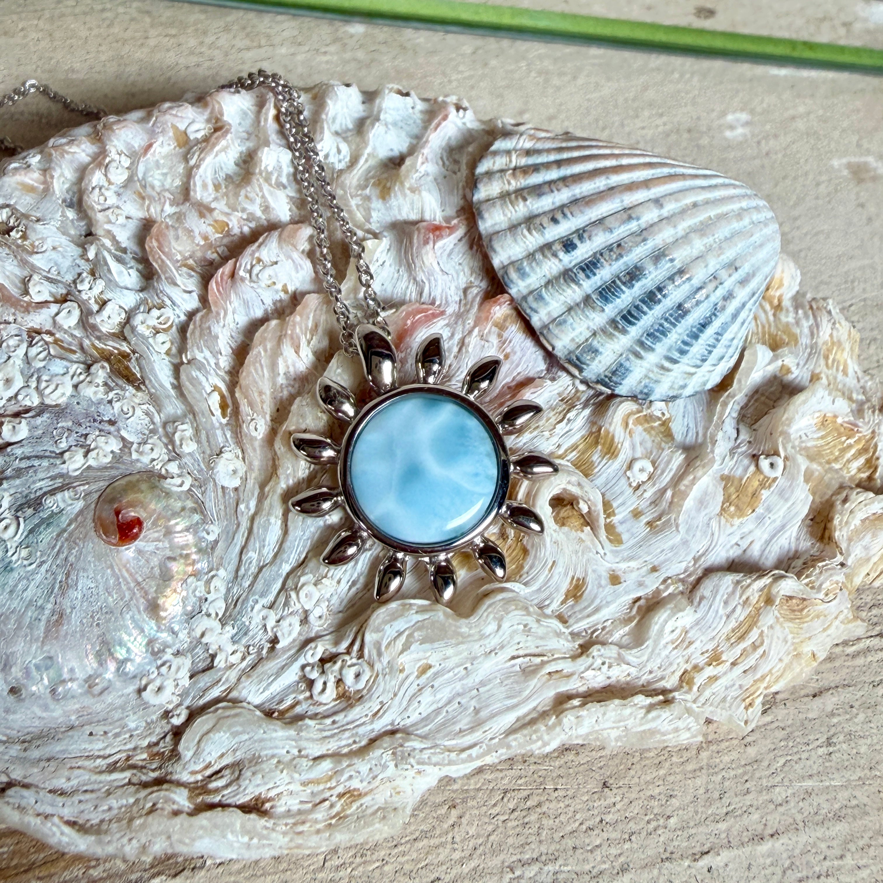 Feine Halskette aus rhodiniertem 925 Silber mit Sonnen-Anhänger und rundem Larimar-Cabochon, 10 mm. Der seltene, hellblaue Stein aus der Dominikanischen Republik erinnert an Meer und Himmel. Gesamtgröße des Anhängers ca. 20 x 19 mm, Ankerkette 45 cm, ca. 1 mm stark. Edler, maritimer Schmuck, geliefert in einer Geschenkbox.