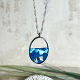 „Riffschatz“ – ovaler Harz-Anhänger mit plastischer 3D-Welle in Blau/Türkis, weißer Schaumkrone und Muschel-/Korallen-Stickern am Grund. Die Sticker sind unter klarem Harz versiegelt. Silber-Legierung, ca. 3,9 × 2,3 cm, an einer ca. 56 cm langen versilberten Kette. Handgefertigt, hochglänzend, jedes Stück ein Unikat.