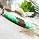 Anhänger aus Nussbaumholz und fluoreszierendem Epoxidharz in Grün-Weiß. Größe ca. 5,8 × 2 cm, Edelstahlöse, Lederkette 45+5 cm. Handgefertigtes Unikat.