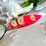 Handgefertigter Surfbrett-Anhänger „Flame Surf“ aus Maserholz und fluoreszierendem Harz in kräftigem Pink. Das Schmuckstück leuchtet bei Schwarzlicht und wird an einer schwarzen Lederkette mit Edelstahl-Karabiner (45 cm + 5 cm Verlängerung) geliefert. Größe ca. 6,7 × 2 cm. Ein Unikat für Surf- und Strandliebhaber, edel verarbeitet und mit Liebe gefertigt.