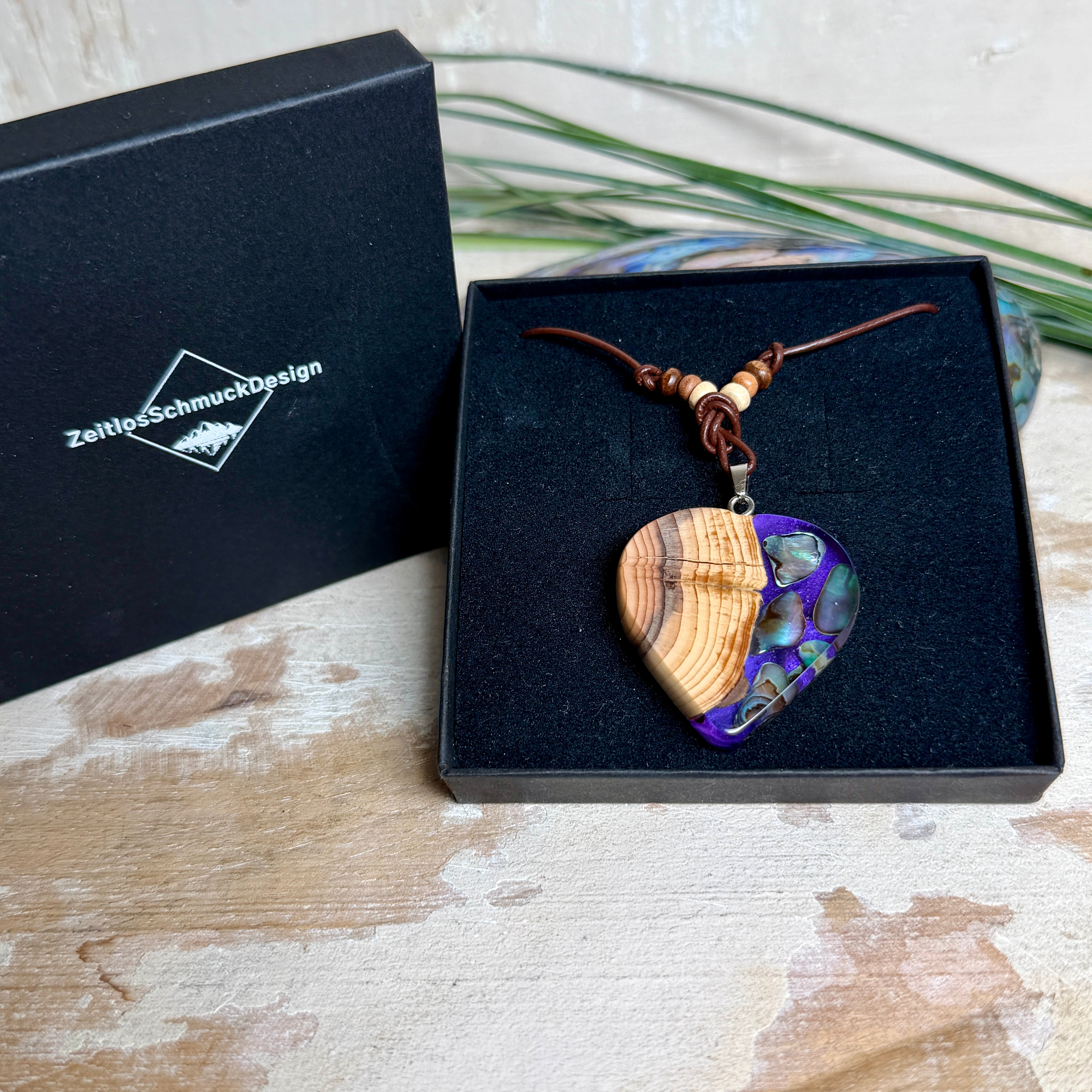 Handgemachter Herzanhänger aus Eibenholz mit lila Harz und Paua-Muschel-Inlay an braunem, verstellbarem Lederband.