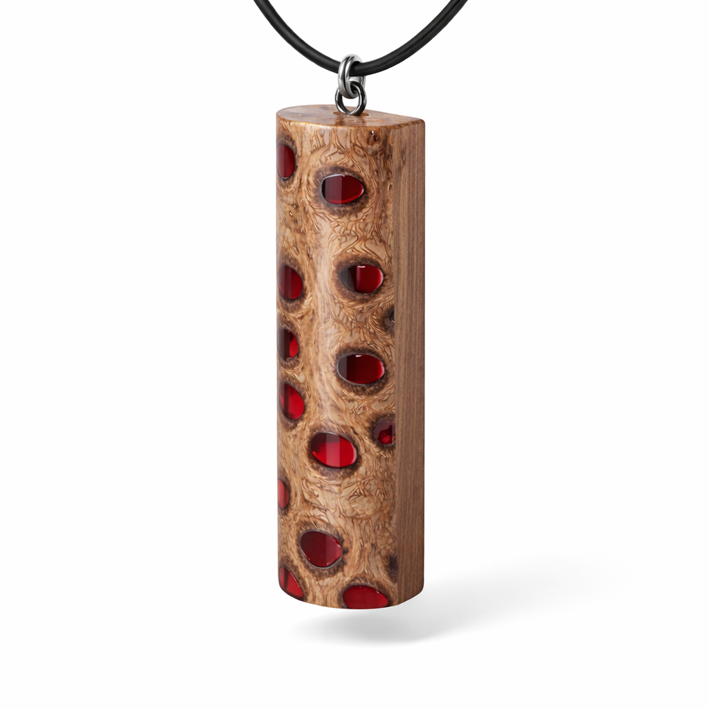 Handgefertigter Halsanhänger aus echtem Banksiazapfen, veredelt mit rotem Harz in den natürlichen Kammern; ca. 5,5 × 1,6 cm. Mit Anhängerschlaufe aus Edelstahl an schwarzer Lederkette (45 cm + 5 cm Verlängerung) mit Edelstahl-Karabiner. Detailaufnahme bzw. Tragebild vor neutralem, natürlichem Hintergrund.