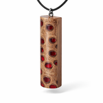 Handgefertigter Halsanhänger aus echtem Banksiazapfen, veredelt mit rotem Harz in den natürlichen Kammern; ca. 5,5 × 1,6 cm. Mit Anhängerschlaufe aus Edelstahl an schwarzer Lederkette (45 cm + 5 cm Verlängerung) mit Edelstahl-Karabiner. Detailaufnahme bzw. Tragebild vor neutralem, natürlichem Hintergrund.