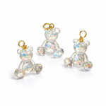 Kleiner Bärchen-Anhänger aus transparentem Harz mit irisierenden Flakes in Regenbogen-Schimmer, goldfarbene Anhängerschlaufe aus Edelstahl. Größe ca. 2,2 × 2,1 cm. Handgefertigtes Unikat; Flakes-Anordnung variiert, vereinzelt kleine Luftbläschen möglich.