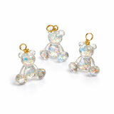 Kleiner Bärchen-Anhänger aus transparentem Harz mit irisierenden Flakes in Regenbogen-Schimmer, goldfarbene Anhängerschlaufe aus Edelstahl. Größe ca. 2,2 × 2,1 cm. Handgefertigtes Unikat; Flakes-Anordnung variiert, vereinzelt kleine Luftbläschen möglich.