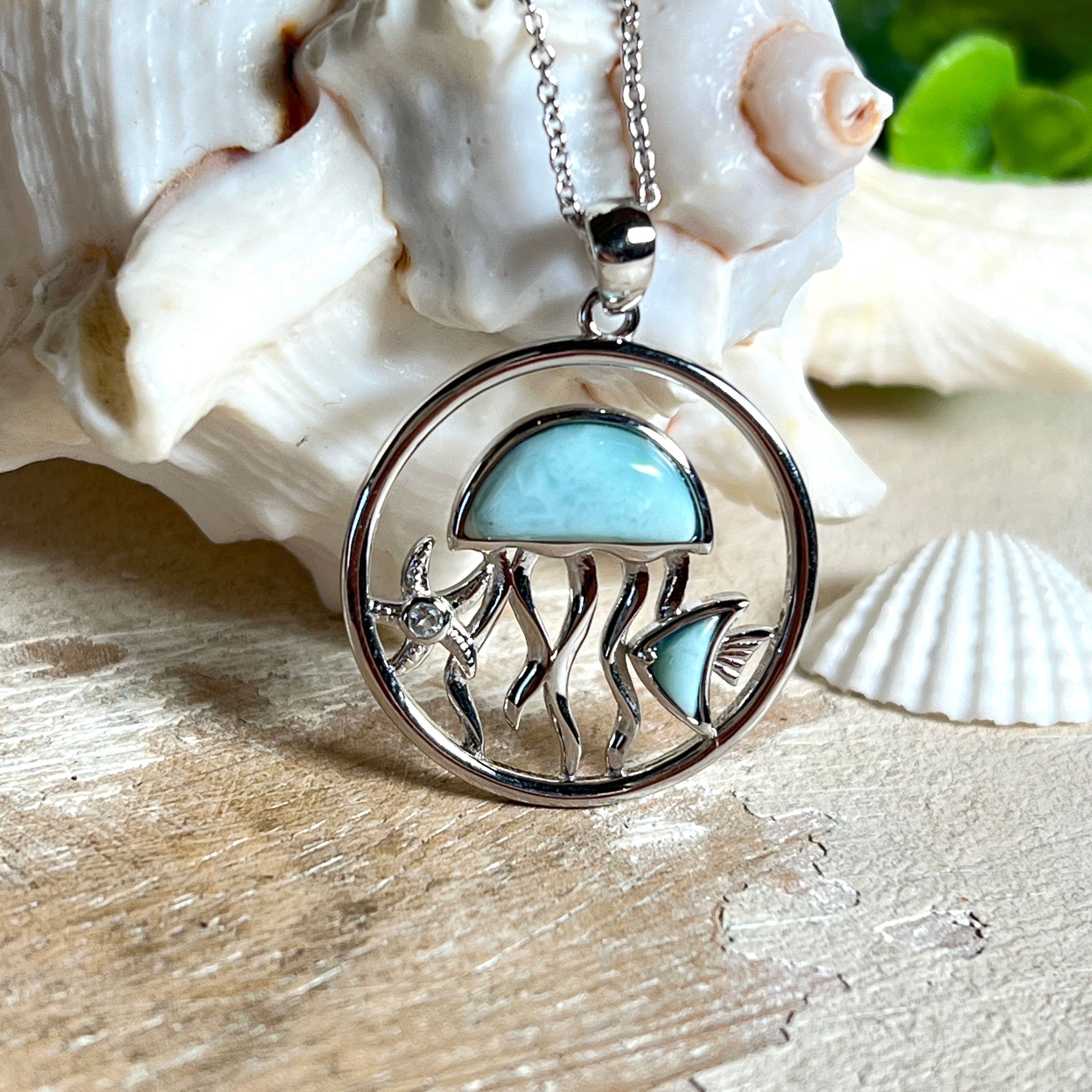 „Sealife“ – runder Anhänger aus rhodiniertem 925 Sterling Silber mit seltenem Larimar und funkelndem Topas. Das maritime Design zeigt eine Qualle, einen Fisch und einen Seestern. Anhängergröße ca. 32 × 26 mm, inklusive 45 cm langer Silberkette (1 mm Stärke). Symbol für die Schönheit und Vielfalt des Ozeans – jedes Stück ein Unikat durch das natürliche Farbspiel des Larimars.