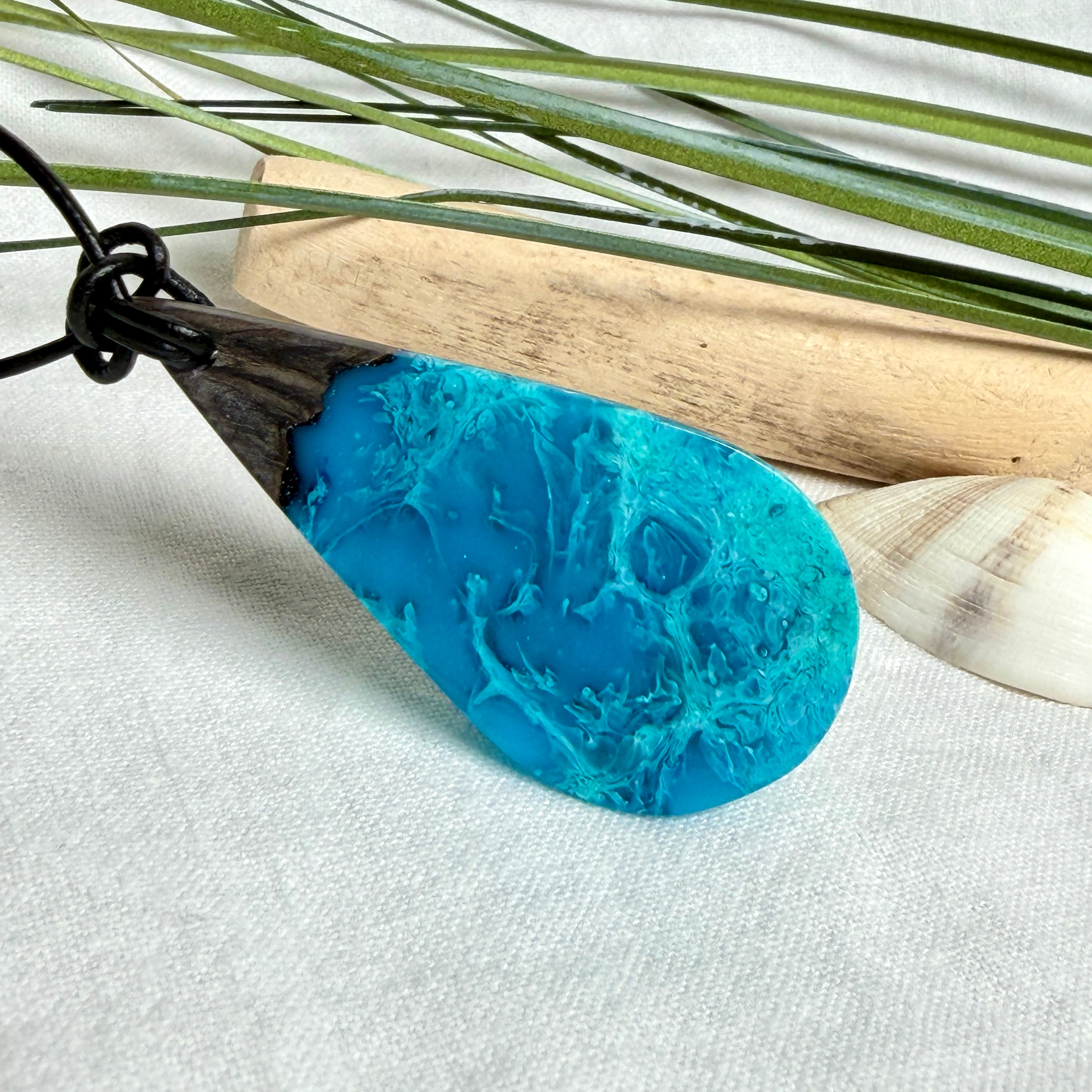Tropfen Anhänger aus dunklem Maserholz und Epoxidharz in Türkis Blau mit weißer Wellenstruktur am schwarzen Lederband, maritimer Holz Harz Naturschmuck