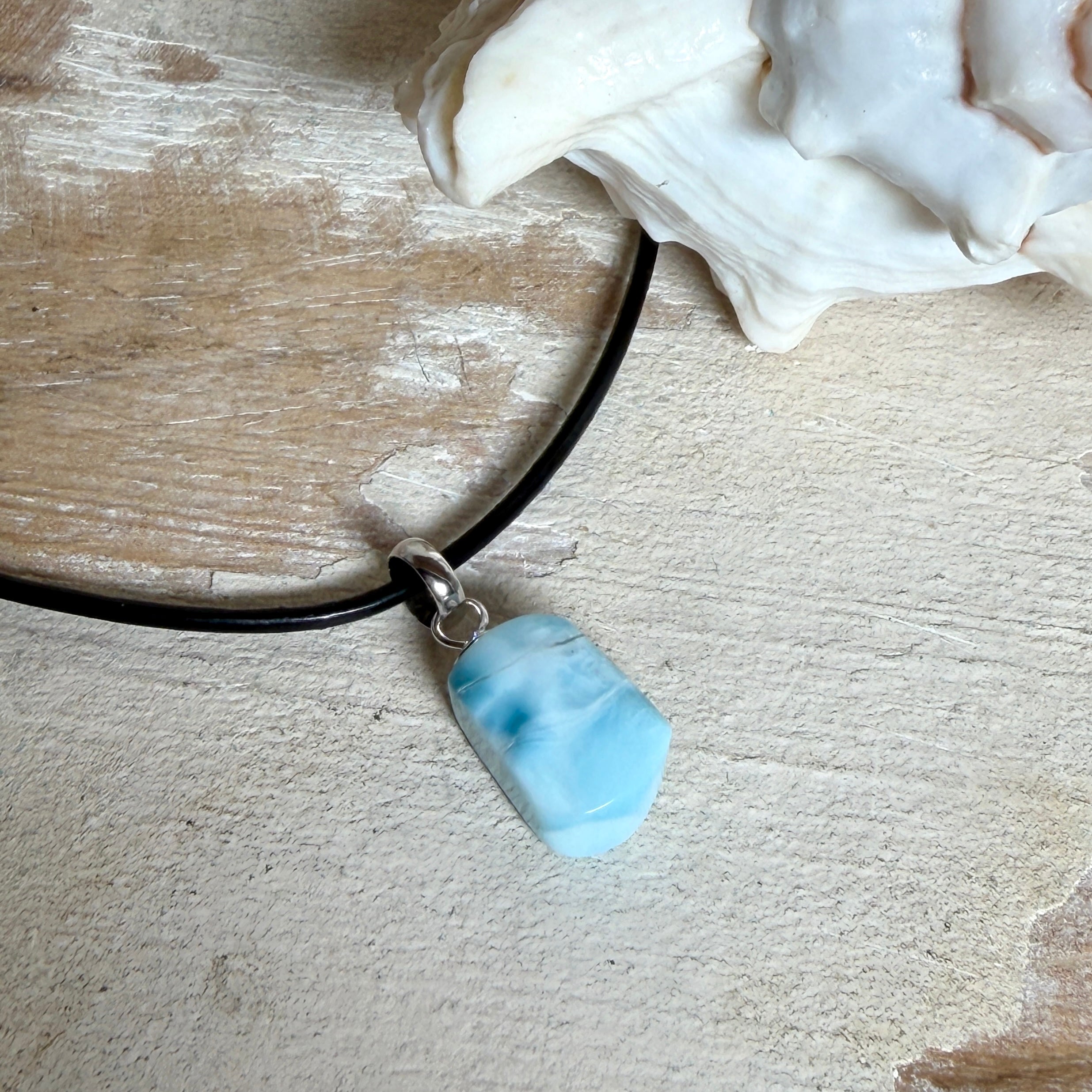 Larimar Freeform Anhänger mit rhodinierter Silberöse an schwarzer Lederkette. Der seltene, kostbare Larimar („Atlantisstein“) zeigt ein lebendiges Muster aus Türkis- und Weißtönen. Beidseitig tragbar, Steingröße ca. 2 x 1 cm, Lederkette 45 cm mit Edelstahl-Karabiner und 5 cm Verlängerung. Natürlicher, maritimer Unikatschmuck.