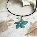 Seestern-Anhänger aus transparentem Harz mit echtem Meersand ( leicht eingefärbt), in blautürkis Strand-Look, mit kleiner Süßwasserperle als Anhänger-Detail. Edelstahlöse, schwarze Lederkette mit Edelstahl-Karabiner und Verlängerung (45 cm + 5 cm). Anhänger ca. 3,5 × 3,5 cm. Handgefertigtes Unikat; vereinzelt kleine Luftbläschen möglich, typisch für Handarbeit.