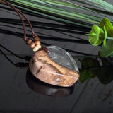 Herzanhänger „Pusteblumenzauber“ aus naturbelassenem Rebholz und klarem Epoxidharz mit schwebenden Pusteblumensamen. Dunkelbraunes, verstellbares Lederband mit kleinen Holzperlen, Anhänger ca. 3,5 × 3,5 cm. Handgefertigtes Unikat von ZeitlosSchmuckDesign.