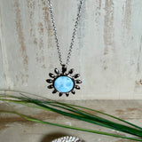 Feine Halskette aus rhodiniertem 925 Silber mit Sonnen-Anhänger und rundem Larimar-Cabochon, 10 mm. Der seltene, hellblaue Stein aus der Dominikanischen Republik erinnert an Meer und Himmel. Gesamtgröße des Anhängers ca. 20 x 19 mm, Ankerkette 45 cm, ca. 1 mm stark. Edler, maritimer Schmuck, geliefert in einer Geschenkbox.