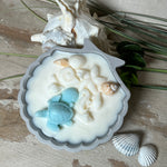 andgefertigte Kerze „Ozeanfreund“ in Jesmonite-Schale (ca. 11 cm). Gefüllt mit nachhaltigem Sojawachs, dekoriert mit echten Muscheln, handgegossenen Wachsmuscheln und einer türkisfarbenen Wachsschildkröte. Maritime Kerze – einzigartig, dekorativ und perfekt als Geschenk oder als Meeres-Deko.