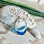 Ovale Halskette „Ocean Crest“ mit 3D-Welle: handgefertigter Harz-Anhänger in Silber-Legierung, Farbverlauf von Tiefblau zu Türkis mit weißer Schaumkrone. Größe ca. 3,9 × 2,3 cm, an einer ca. 56 cm langen versilberten Kette. Glänzende Oberfläche, maritimer Look, Unikat-Handarbeit.