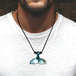 Maritimer Walflossen-Anhänger aus Holz und türkis-weißem Harz an schwarzem Lederband, getragen von einem männlichen Model mit weißem T-Shirt – handgefertigter Unisex-Schmuck von ZeitlosSchmuckDesign für Strand, Alltag und Surfer-Style.