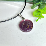 Runder Pusteblumen-Anhänger aus Harz, Hintergrund Brombeerfarben. Durchmesser 22 mm, Edelstahlöse, Lederkette verstellbar mit Edelstahlverschluss.