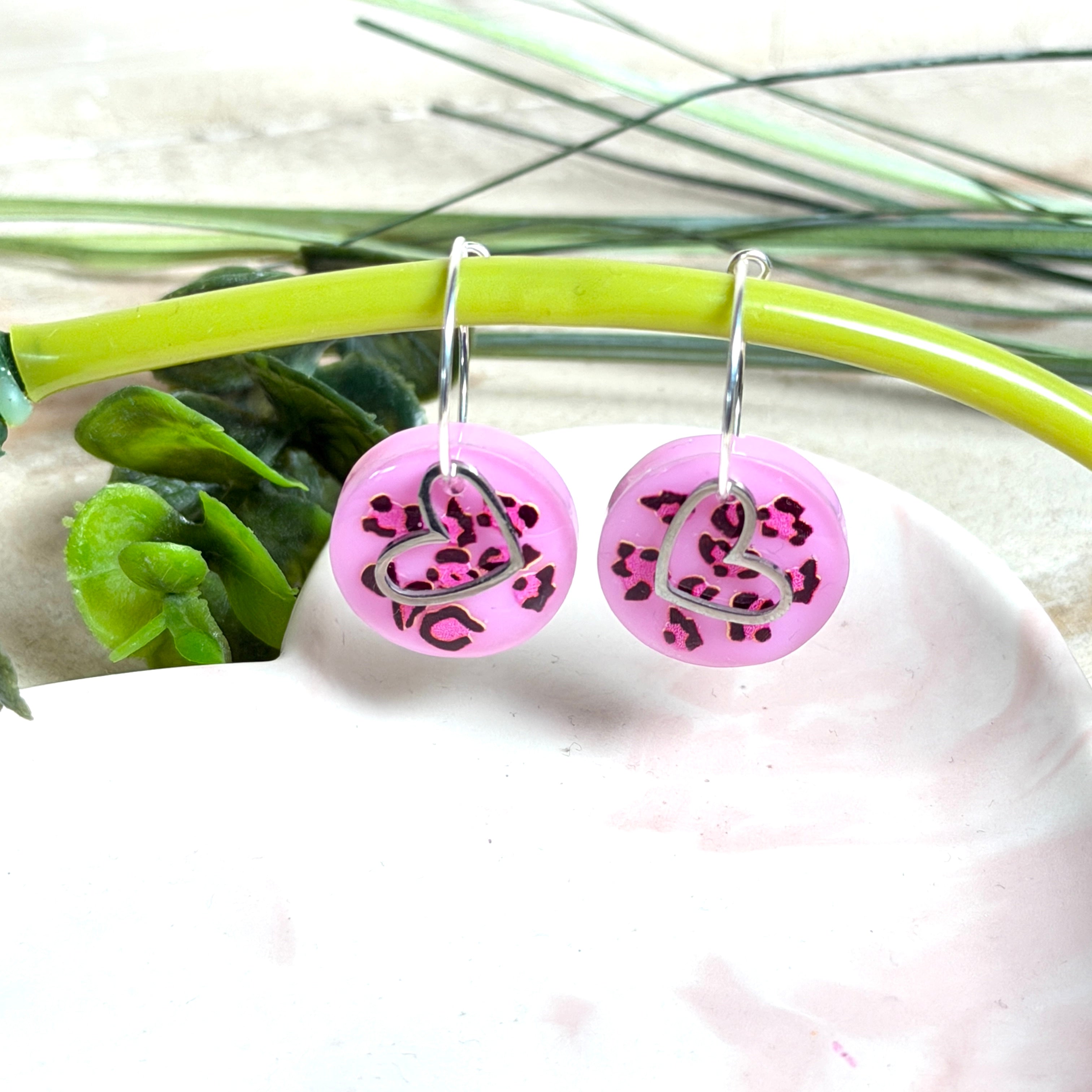 Handgemachte Leo-Creolen aus 925 Silber: Silber-Creolen 16 mm mit rosa Harz-Scheibe (2 cm) im Leoparden-Look und Edelstahl-Herzanhänger. Hängende Ohrringe in Animal-Print Stil, Gesamtlänge ca. 3,5 cm. Resin-Ohrringe für Alltag, Party oder Festival, femininer Statement-Schmuck in Rosa/Pink mit silberfarbenen Metallteilen. Einzeln gegossen, jedes Paar ein Unikat; leichte Abweichungen im Muster, Farbspiel und kleine Luftbläschen sind möglich und typisch für Handarbeit.