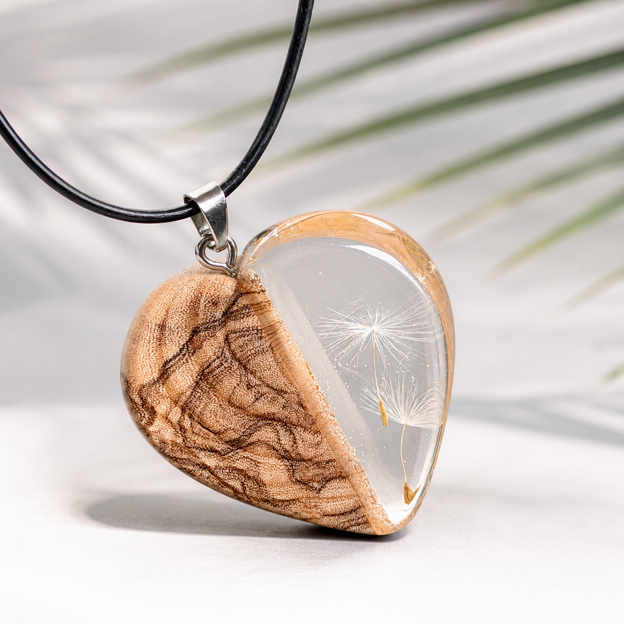 Pusteblumen Herzanhänger aus Olivenholz und glasklarem Epoxidharz, echte Löwenzahnsamen sichtbar, schwarze Lederkette, handgefertigter Naturschmuck für Damen, heller Hintergrund