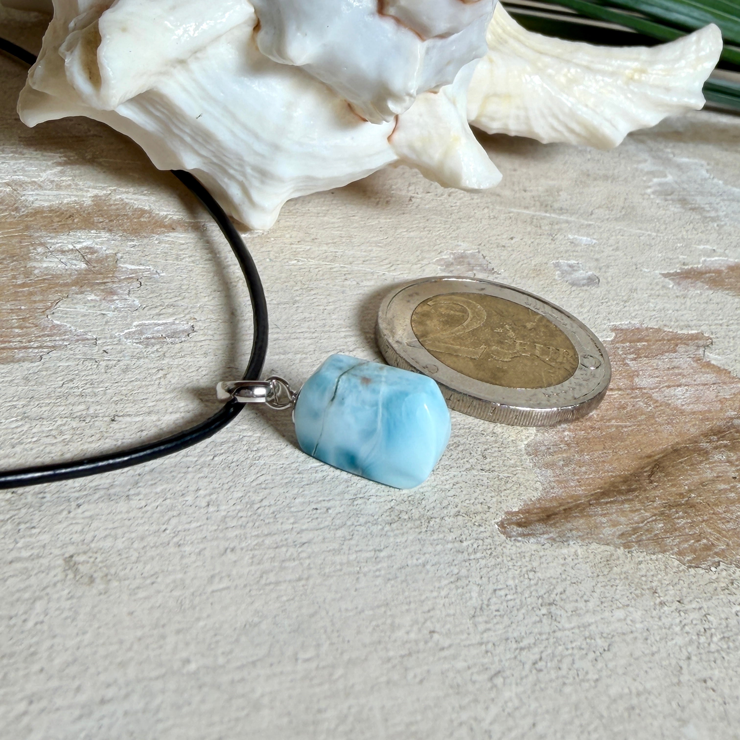 Larimar Freeform Anhänger mit rhodinierter Silberöse an schwarzer Lederkette. Der seltene, kostbare Larimar („Atlantisstein“) zeigt ein lebendiges Muster aus Türkis- und Weißtönen. Beidseitig tragbar, Steingröße ca. 2 x 1 cm, Lederkette 45 cm mit Edelstahl-Karabiner und 5 cm Verlängerung. Natürlicher, maritimer Unikatschmuck.