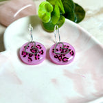 Handgemachte Leo-Creolen aus 925 Silber: Silber-Creolen 16 mm mit rosa Harz-Scheibe (2 cm) im Leoparden-Look und Edelstahl-Herzanhänger. Hängende Ohrringe in Animal-Print Stil, Gesamtlänge ca. 3,5 cm. Resin-Ohrringe für Alltag, Party oder Festival, femininer Statement-Schmuck in Rosa/Pink mit silberfarbenen Metallteilen. Einzeln gegossen, jedes Paar ein Unikat; leichte Abweichungen im Muster, Farbspiel und kleine Luftbläschen sind möglich und typisch für Handarbeit.