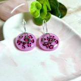 Handgemachte Leo-Creolen aus 925 Silber: Silber-Creolen 16 mm mit rosa Harz-Scheibe (2 cm) im Leoparden-Look und Edelstahl-Herzanhänger. Hängende Ohrringe in Animal-Print Stil, Gesamtlänge ca. 3,5 cm. Resin-Ohrringe für Alltag, Party oder Festival, femininer Statement-Schmuck in Rosa/Pink mit silberfarbenen Metallteilen. Einzeln gegossen, jedes Paar ein Unikat; leichte Abweichungen im Muster, Farbspiel und kleine Luftbläschen sind möglich und typisch für Handarbeit.