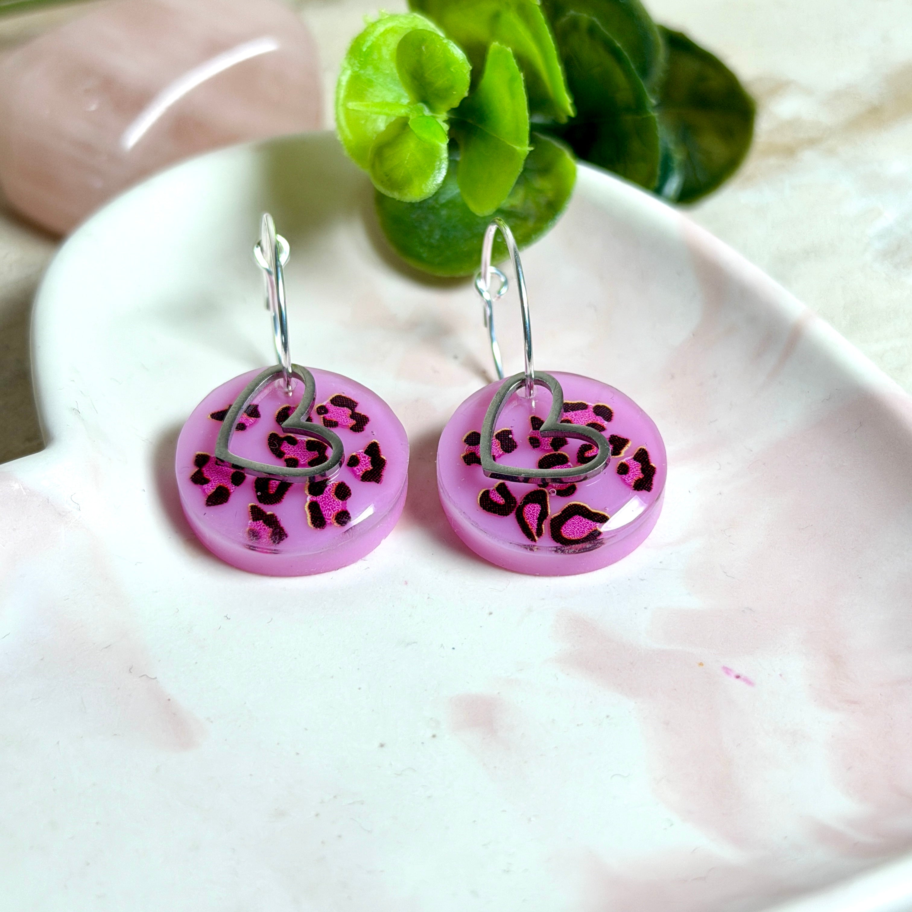 Handgemachte Leo-Creolen aus 925 Silber: Silber-Creolen 16 mm mit rosa Harz-Scheibe (2 cm) im Leoparden-Look und Edelstahl-Herzanhänger. Hängende Ohrringe in Animal-Print Stil, Gesamtlänge ca. 3,5 cm. Resin-Ohrringe für Alltag, Party oder Festival, femininer Statement-Schmuck in Rosa/Pink mit silberfarbenen Metallteilen. Einzeln gegossen, jedes Paar ein Unikat; leichte Abweichungen im Muster, Farbspiel und kleine Luftbläschen sind möglich und typisch für Handarbeit.