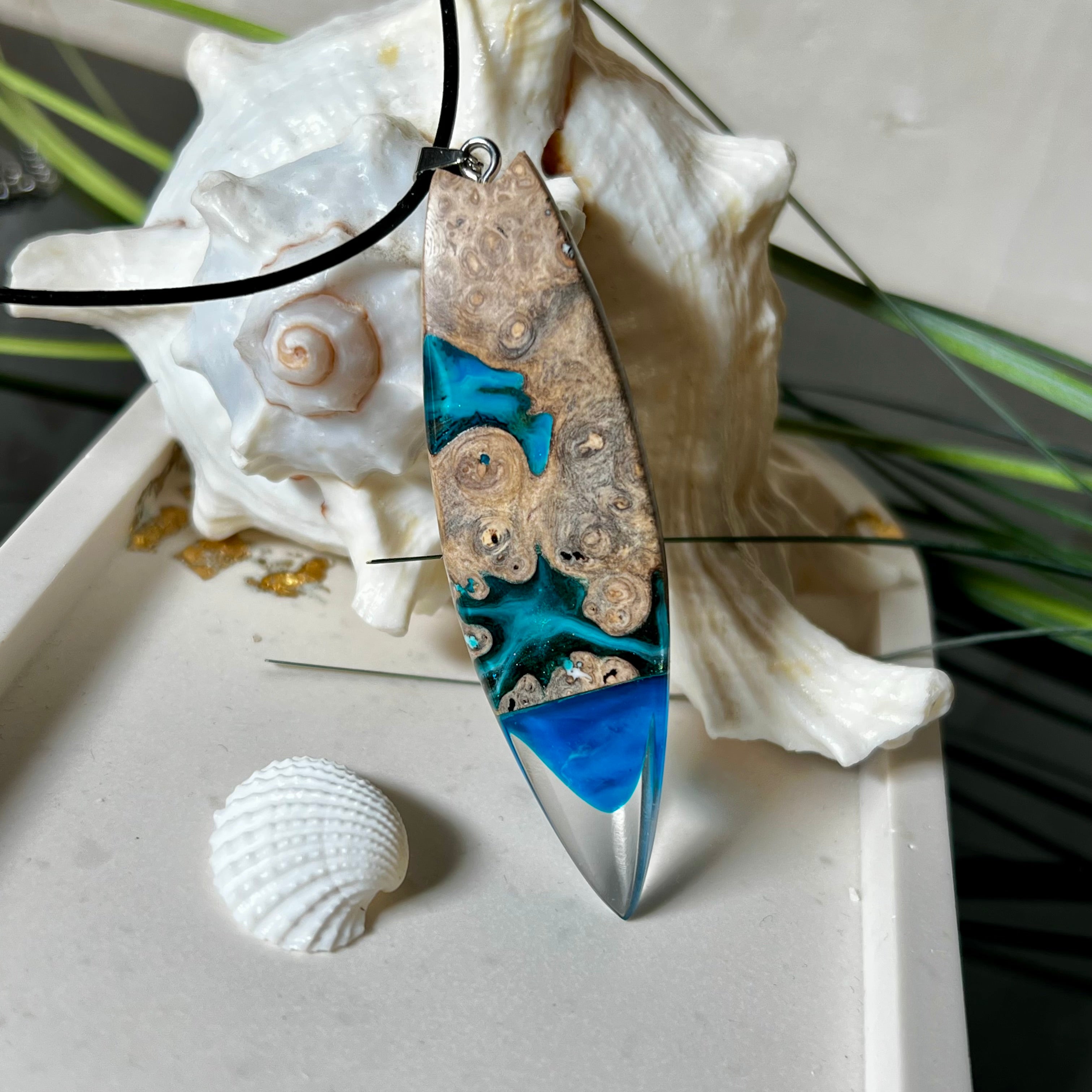 Handgefertigter Surfbrett-Anhänger aus Maserholz und transparentem Harz mit Farbverlauf in Blau und Weiß. Die natürliche Maserung des Holzes trifft auf ozeanartige Harzstrukturen. Größe ca. 6,7 x 2 cm, mit Edelstahlöse und Lederband inkl. Karabinerverschluss (45 cm + 5 cm Verlängerung). Jedes Stück ist ein Unikat – maritim, modern und mit viel Liebe gefertigt.