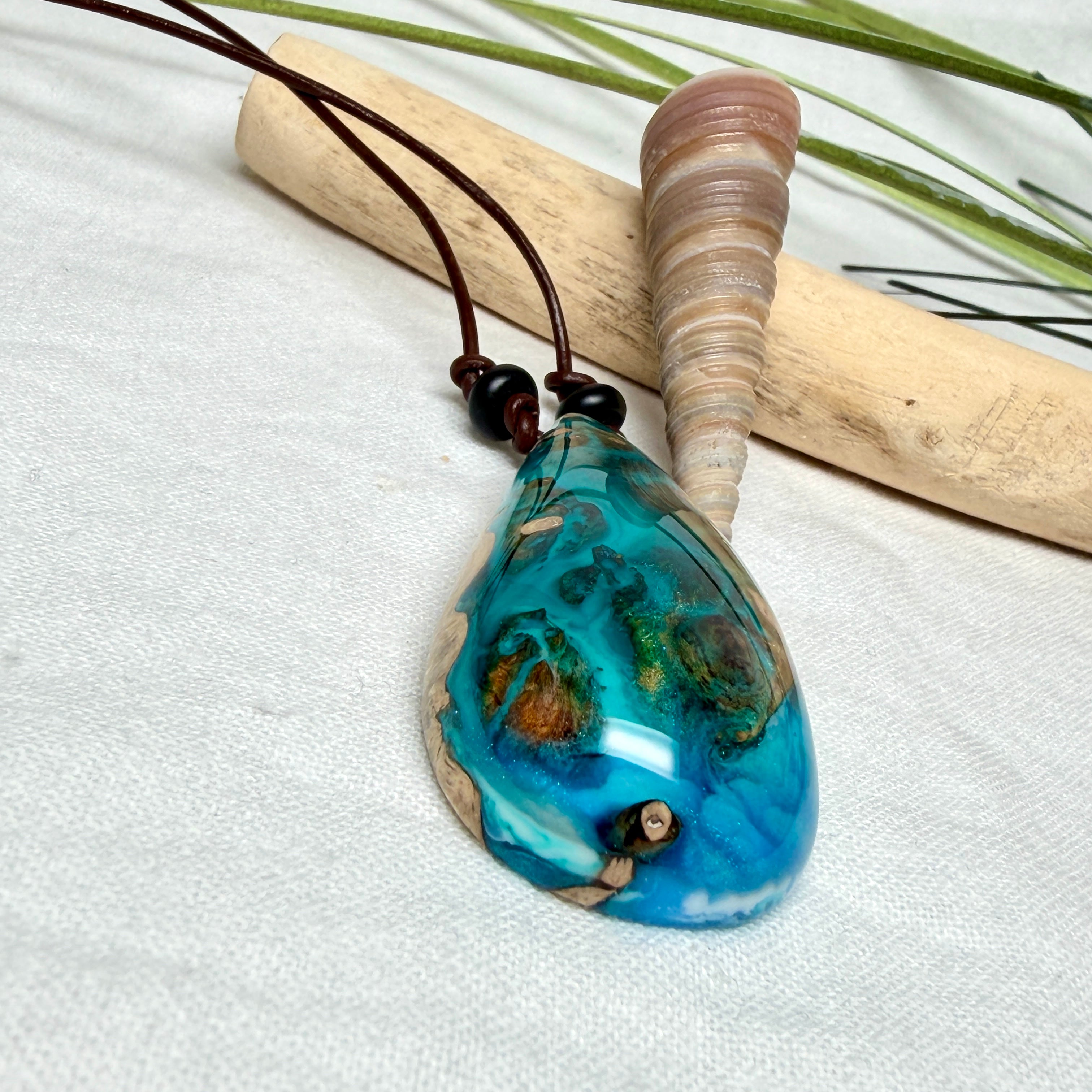 Holz-Harz-Anhänger aus Maserholz mit türkis-blauem Epoxidharz in Tropfenform am verstellbaren Lederband mit Onyxperlen, handgemachter maritimer Naturschmuck