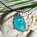 Edle Halskette „Blue Essence“ mit handgefertigtem türkisfarbenem Seeglas-Anhänger und Edelstahl-Flosse. Die Kette besteht aus schwarzer Lederkordel mit Karabinerverschluss und Verlängerung aus Edelstahl. Das matte Seeglas reflektiert Licht wie Meereswasser – ideal für Strandliebhaber und Naturliebhaber.