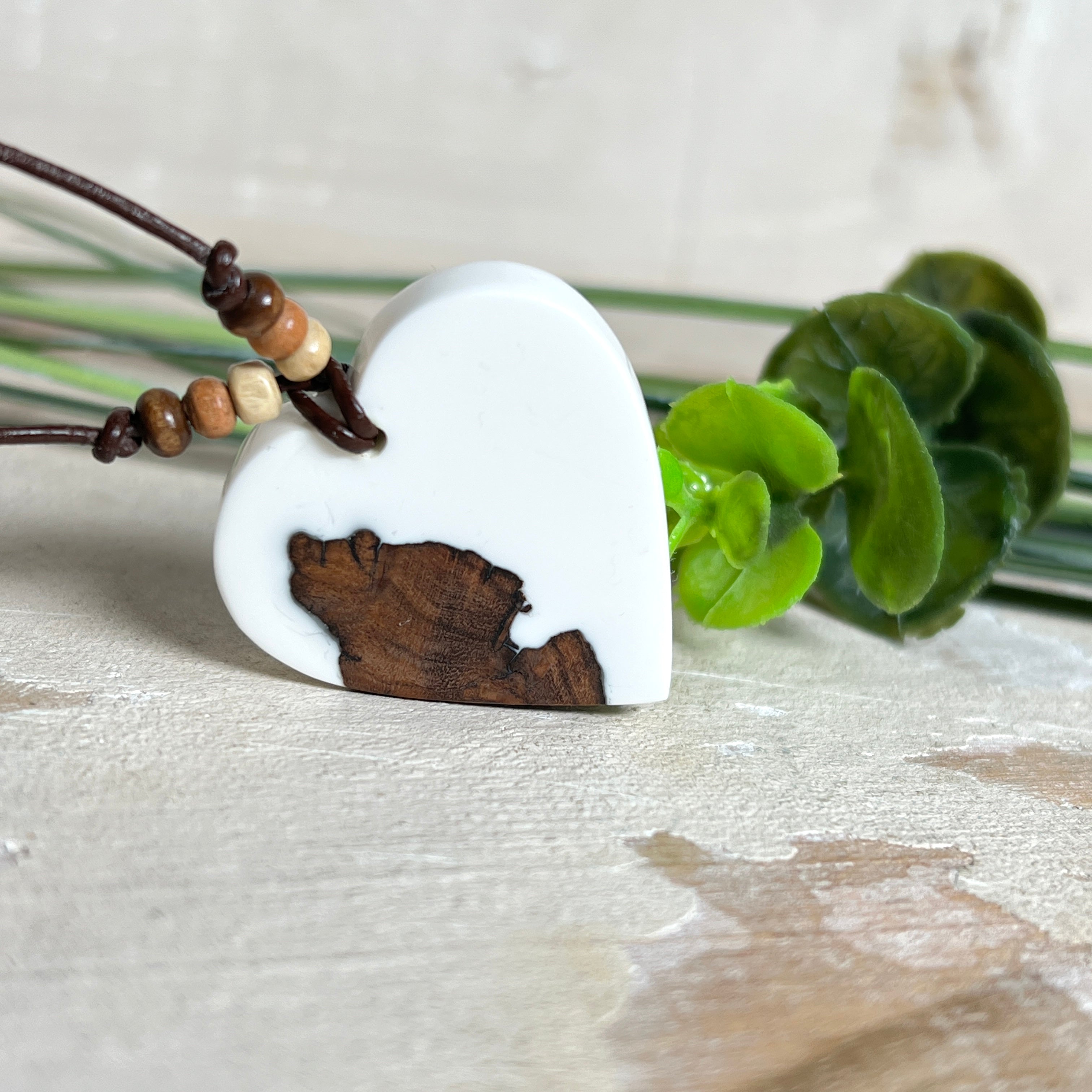 Herzanhänger „Pure Heart“ aus Maserholz und weißem Epoxidharz. Handgefertigtes Unikat mit kontrastreichem Design – die natürliche Maserung des Holzes trifft auf die klare Reinheit von Weiß. Größe ca. 3,5 × 3,5 cm. Verstellbares Lederband (23–41 cm) mit Holzperlen. Ein edles Schmuckstück, inspiriert von Natur und Liebe.
