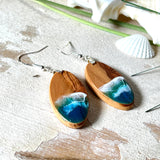 Handgefertigte Ohrringe „Wave Harmony“ aus Olivenholz und Epoxidharz in Blau-, Türkis- und Weißtönen. Das Design erinnert an Meereswellen am Strand. Jeder Ohrring ist ein Unikat mit individueller Maserung. Versilberte, nickelfreie und bleifreie Anhängerschlaufe, 925 Silber Ohrhaken. Maritimer Schmuck – perfekt für Meerliebhaber und als edles Geschenk.
