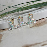 Kleiner Bärchen-Anhänger aus transparentem Harz mit irisierenden Flakes in Regenbogen-Schimmer, goldfarbene Anhängerschlaufe aus Edelstahl. Größe ca. 2,2 × 2,1 cm. Handgefertigtes Unikat; Flakes-Anordnung variiert, vereinzelt kleine Luftbläschen möglich.