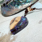 Handgemachter Herzanhänger aus Eibenholz mit lila Harz und Paua-Muschel-Inlay an braunem, verstellbarem Lederband.