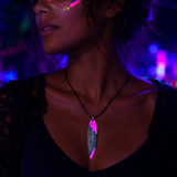I-generiertes Schwarzlicht-Tragebild der Halskette „Pink Glow“ mit handgefertigtem Surfbrett Anhänger aus Olivenholz und fluoreszierendem Epoxidharz in Pink-Weiß, schwarze Lederkette, maritimer Damen Schmuck mit UV-Neon-Effekt.