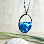 „Riffschatz“ – ovaler Harz-Anhänger mit plastischer 3D-Welle in Blau/Türkis, weißer Schaumkrone und Muschel-/Korallen-Stickern am Grund. Die Sticker sind unter klarem Harz versiegelt. Silber-Legierung, ca. 3,9 × 2,3 cm, an einer ca. 56 cm langen versilberten Kette. Handgefertigt, hochglänzend, jedes Stück ein Unikat.