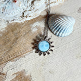 Feine Halskette aus rhodiniertem 925 Silber mit Sonnen-Anhänger und rundem Larimar-Cabochon, 10 mm. Der seltene, hellblaue Stein aus der Dominikanischen Republik erinnert an Meer und Himmel. Gesamtgröße des Anhängers ca. 20 x 19 mm, Ankerkette 45 cm, ca. 1 mm stark. Edler, maritimer Schmuck, geliefert in einer Geschenkbox.