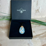 Handgefertigter Tropfenanhänger aus Maserholz und klarem Epoxidharz in Aquatönen. Im Harz sind echte Muscheln und ein kleiner Seestern eingebettet. Durch die besondere Mehrschicht-Gießtechnik wirkt es, als würden die Muscheln im Wasser schweben. Größe ca. 3,8 × 2 cm. Verstellbares Lederband (24–44 cm) mit Holzperlen. Maritimes Unikat.