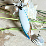 Handgefertigter Surfbrett-Anhänger „Ocean Glide“ aus Maserholz und Epoxidharz in verschiedenen Blau-, und Weißtönen. Der ca. 6,5 × 2 cm große Anhänger wird an einem verstellbaren Lederband (26–46 cm) mit Holzperlen geliefert. Ein maritimes Unikat mit natürlicher Holzmaserung, das die Schönheit des Meeres einfängt.