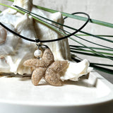 Handgefertigter Anhänger in Seesternform aus echtem Meersand und transparentem Harz. Verziert mit einer natürlichen Süßwasserperle. Edelstahlöse, Lederkette mit Karabinerverschluss (45 cm + 5 cm Verlängerung). Maritimer Schmuck im Unikatcharakter – inspiriert vom Meer und handgefertigt mit Liebe zum Detail. Perfektes Geschenk für Strandliebhaber.