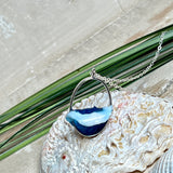 Ovale Halskette „Ocean Crest“ mit 3D-Welle: handgefertigter Harz-Anhänger in Silber-Legierung, Farbverlauf von Tiefblau zu Türkis mit weißer Schaumkrone. Größe ca. 3,9 × 2,3 cm, an einer ca. 56 cm langen versilberten Kette. Glänzende Oberfläche, maritimer Look, Unikat-Handarbeit.