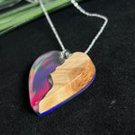 Handgefertigter Herzanhänger aus Maserholz und schimmerndem Opalharz, inspiriert von den Farben der Aurora Borealis. Das Holz zeigt eine feine Maserung, das Harz leuchtet in Rosa-, Blau- und Violetttönen. Mit zarter 925 Silber-Ankerkette (1 mm stark, 45 cm lang) und Silberöse. Ein edles Unikat in liebevoller Handarbeit gefertigt.