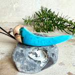 Handgefertigter Anhänger aus Edelholz und transparent-türkisblauem und weißen Epoxidharz, glatt poliert. Größe ca. 6,5 × 2,0 cm. Mit Edelstahlöse an schwarzer Lederkette (45 cm + 5 cm Edelstahl-Verlängerung, Karabiner). Moderner, unisex tragbarer Schmuck mit natürlicher Holzmaserung; kleine Lufteinschlüsse sind charakteristisch.