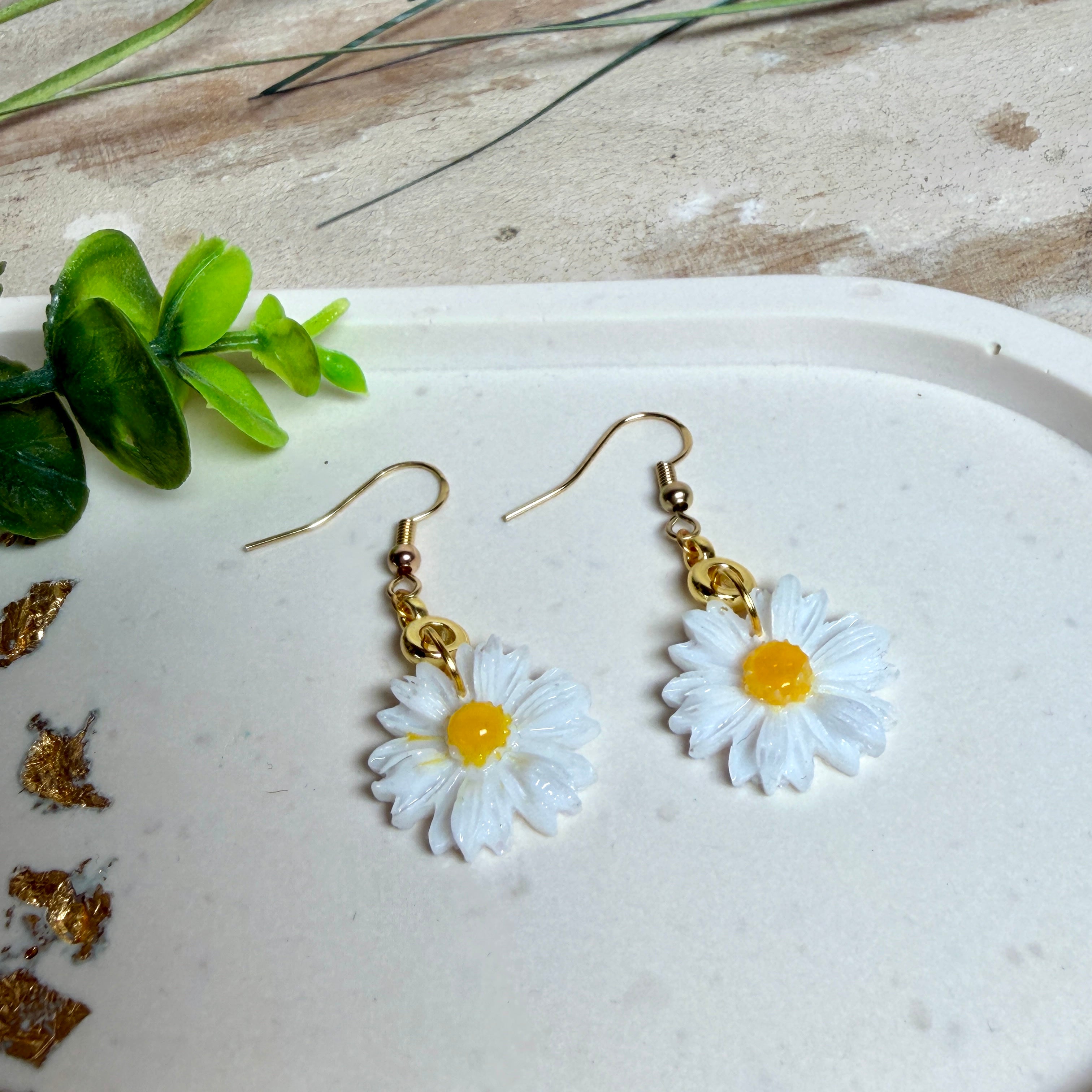 Handgefertigte Gänseblümchen-Ohrringe aus Harz mit 925 vergoldeten Ohrhaken, weiße Blüte mit gelbem Zentrum, goldfarbene Details, Länge ca. 4,5 cm.