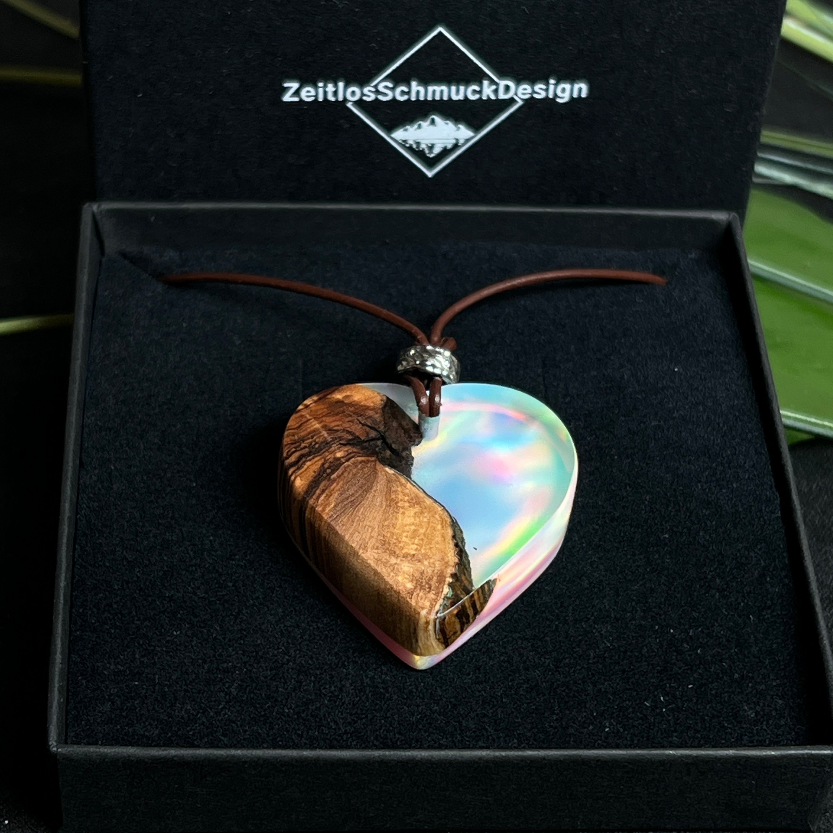 Handgefertigter Herzanhänger aus Olivenholz und schimmerndem Opalharz (Resin Colloidal Imitation Opal) – ein hochwertiges Harz mit feinen, lichtreflektierenden Partikeln, die an echte Opale erinnern. Je nach Licht schimmert der Anhänger in Regenbogenfarben. Mit braunem Lederband und silberfarbener Perle. Jedes Stück ein liebevoll gefertigtes Unikat.