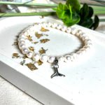 Handgefertigtes Armband aus echten Süßwasserperlen (ca. 6-7 mm), elastisch aufgezogen mit einem Edelstahl-Charm in Form einer Walflosse. Maritimes Design mit Bedeutung – stilvoll, natürlich und elegant. Größe ca. 17,5 cm. Ideal als Geschenk für Meeresliebhaberinnen oder für sich selbst.