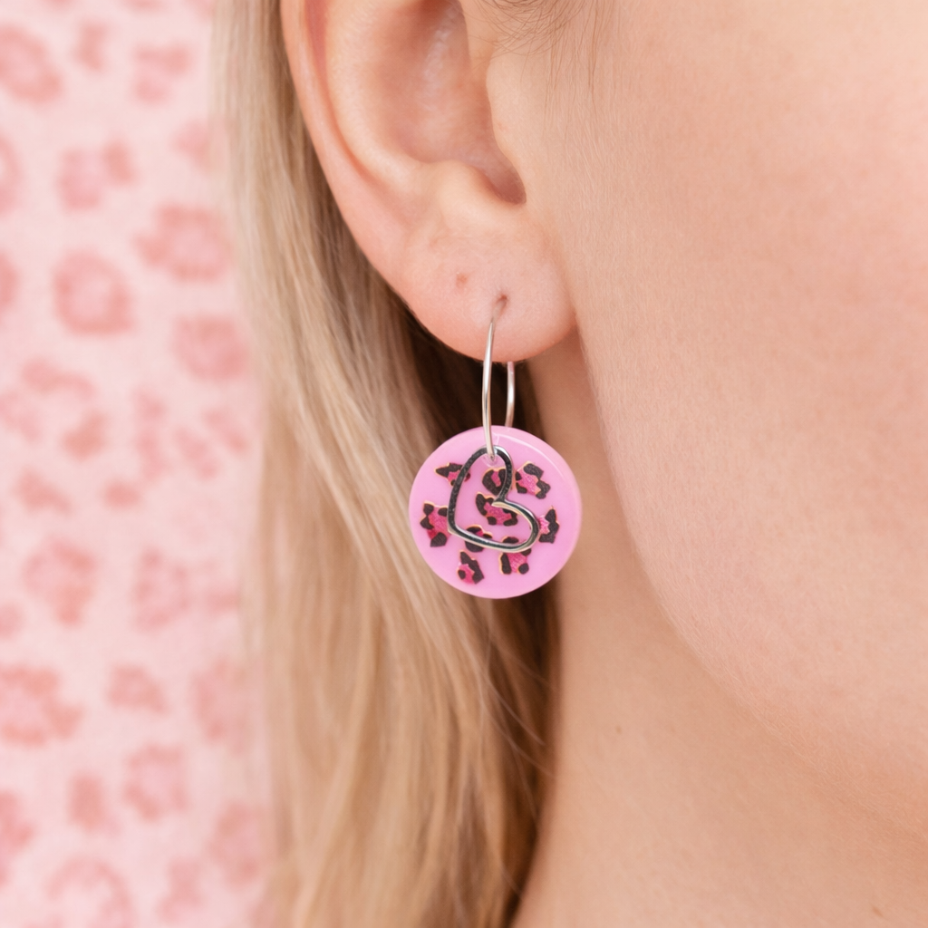 Handgemachte Leo-Creolen aus 925 Silber: Silber-Creolen 16 mm mit rosa Harz-Scheibe (2 cm) im Leoparden-Look und Edelstahl-Herzanhänger. Hängende Ohrringe in Animal-Print Stil, Gesamtlänge ca. 3,5 cm. Resin-Ohrringe für Alltag, Party oder Festival, femininer Statement-Schmuck in Rosa/Pink mit silberfarbenen Metallteilen. Einzeln gegossen, jedes Paar ein Unikat; leichte Abweichungen im Muster, Farbspiel und kleine Luftbläschen sind möglich und typisch für Handarbeit.