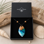 Schmuckbox-Bild BRANDUNG – handgefertigter Holz-Harz-Anhänger aus Maserholz und Epoxidharz in Blau, Türkis und Weiß, maritimer Naturschmuck am verstellbaren Lederband mit Holzperlen, Unikat in schwarzer ZeitlosSchmuckDesign Schmuckbox.